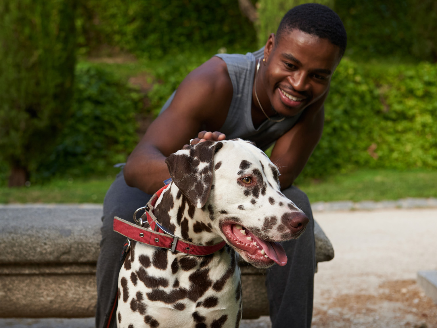 zwarte man zit met grote bruin gevlekte Dalmatische hond