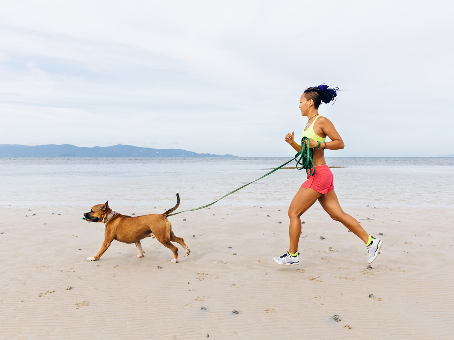 Vrouw die met hond op strand loopt