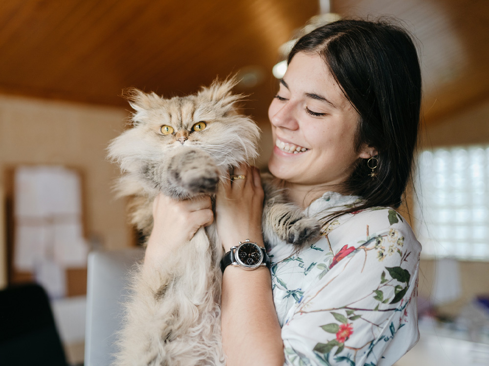 Vrouw die donzige Perzische kat vasthoudt