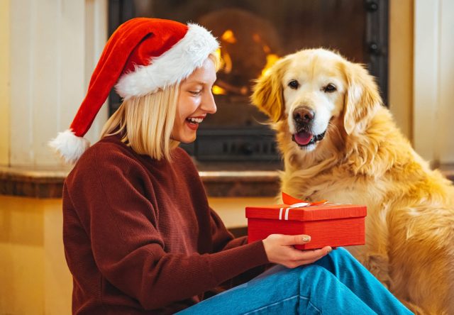 Vrouw en hond openen kerstcadeaus