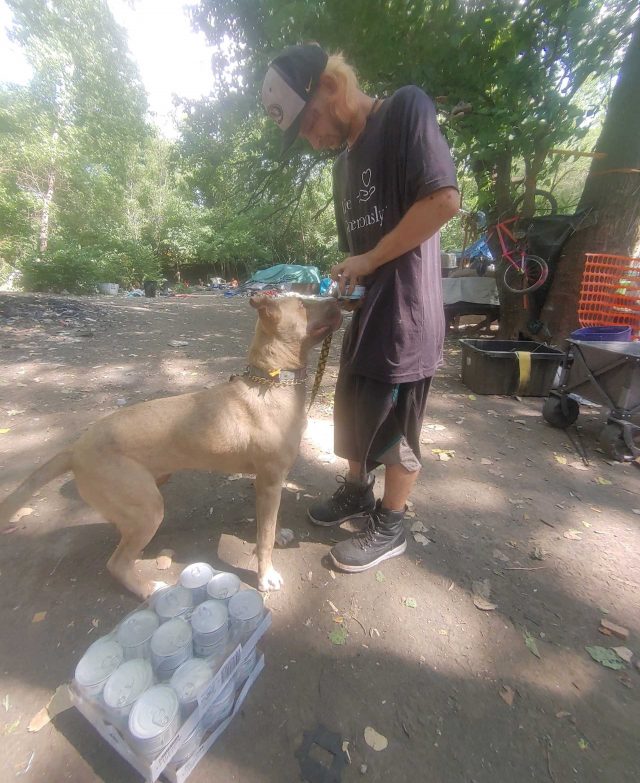 Dakloze mens die hondenvoer geeft